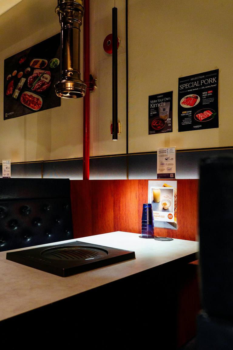A Korean BBQ booth with a built-in charcoal grill and extraction hood